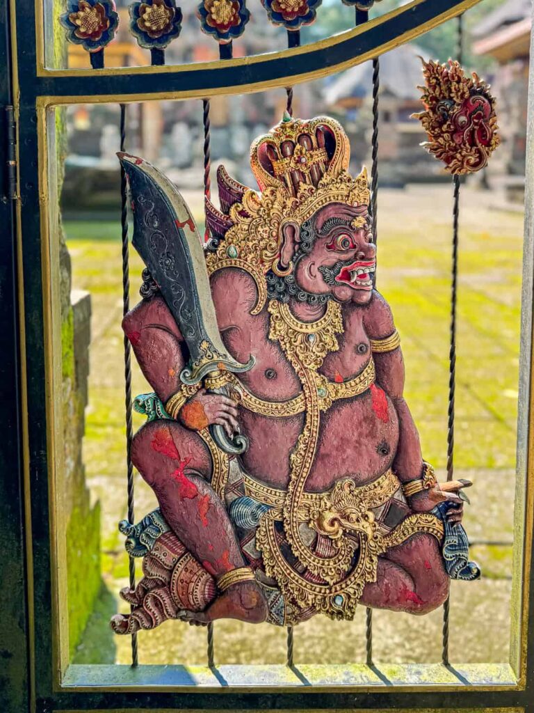 Ozdoba przedstawiająca dawnego wojownika na metalowej bramie w Mandala Wisata Wenara Wana (Małpi Las) w Ubud