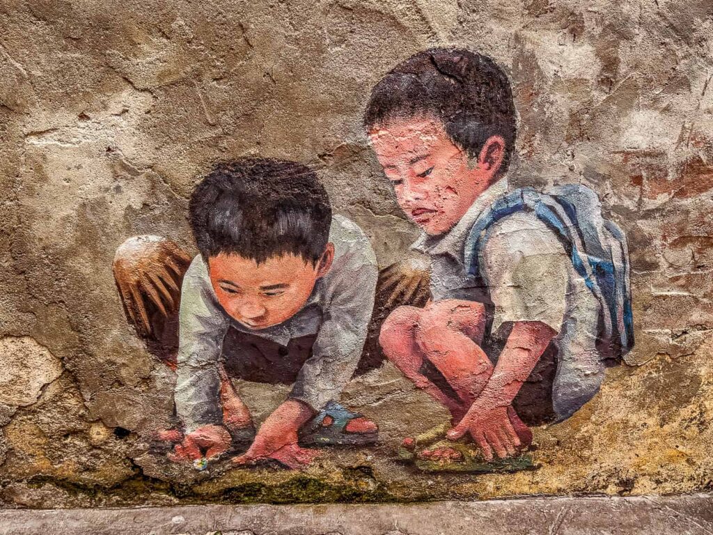 Mural na starej ścianie w Kwai Chai Hong przedstawiający dwóch kucających chłopców grających w szklane kulki. Jeden z nich ma na plecach niebieski szkolny plecak.